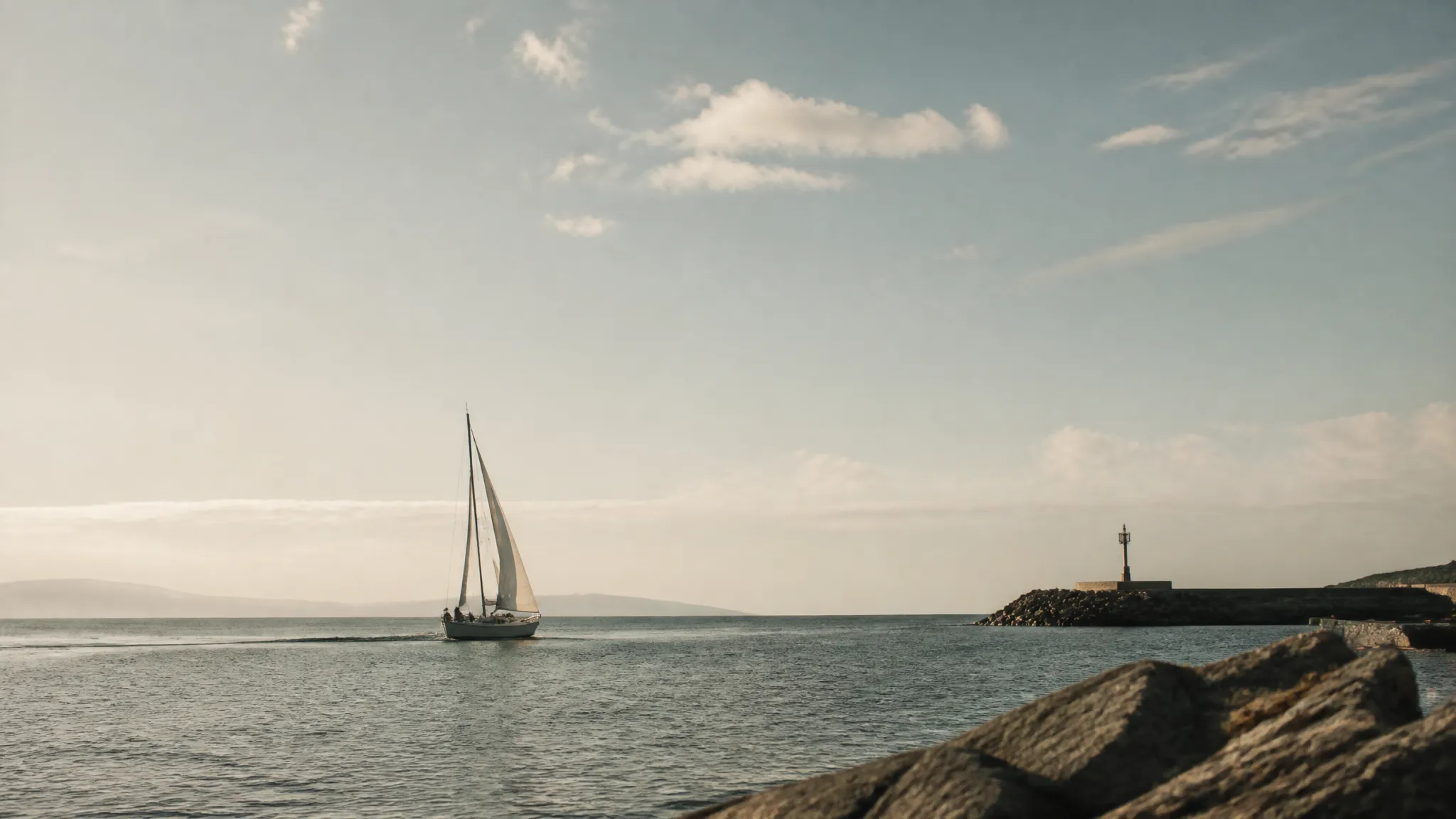A sailboat catching wind as it leaves a calm harbour